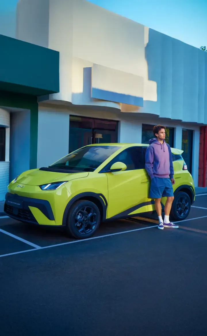 BYD DOLPHIN SURF estacionado e com rapaz encostado ao carro